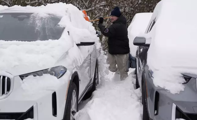 The BMW Store lot technician Cary Fallath clears snow from new BMWs in Silverton, Ohio, Tuesday, Jan. 7, 2025. (AP Photo/Carolyn Kaster)