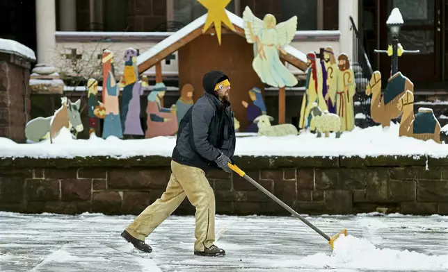 Josh Williams, of Johnstown, shovels snow from the walkway at First United Methodist Church on Vine Street in downtown Johnstown, Pa., Monday, Jan. 6, 2025. (Thomas Slusser/The Tribune-Democrat via AP)