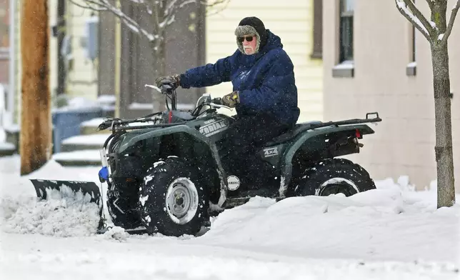 John Lovrich uses his Yamaha Kodiak 450 4x4 all-terrain vehicle to plow snow near his home in the Cambria City section of Johnstown, Pa., Monday, Jan. 6, 2025. (Thomas Slusser/The Tribune-Democrat via AP)