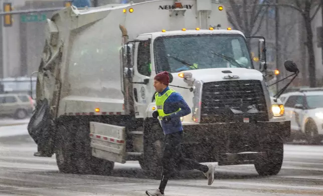 A runner passes on a snowy morning as it falls over Center City, Philadelphia, Monday, Jan. 6, 2025. (Alejandro A. Alvarez/The Philadelphia Inquirer via AP)