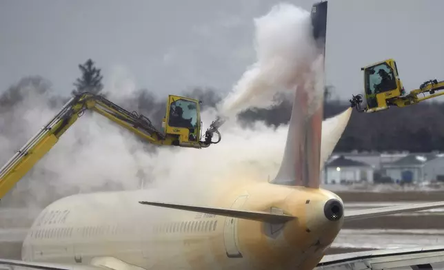 A Delta Air Lines jet is deiced before takeoff at the Detroit Metropolitan Wayne County Airport in Romulus, Mich., Monday, Jan. 6, 2025. (AP Photo/Charlie Riedel)