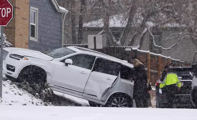 Motorists survey damage done to a utility vehicle in a crash at an intersection as a winter storm sweeps over the intermountain West and across the country Tuesday, Jan. 7, 2025, in southeast Denver. (AP Photo/David Zalubowski)