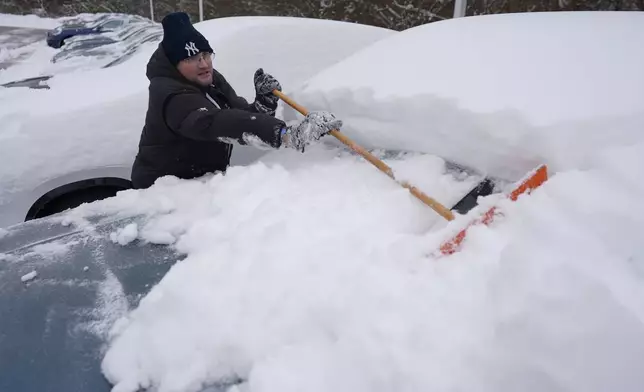 Cary Fallath, the BMW Store lot technician, clears snow from new cars in Silverton, Ohio, Tuesday, Jan. 7, 2025. (AP Photo/Carolyn Kaster)