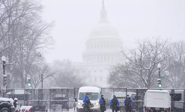 Law enforcement officers stand guard at the Capitol as snow falls ahead of a joint session of Congress to certify the votes from the Electoral College in the presidential election, in Washington, Monday, Jan. 6, 2025. (AP Photo/Matt Rourke)