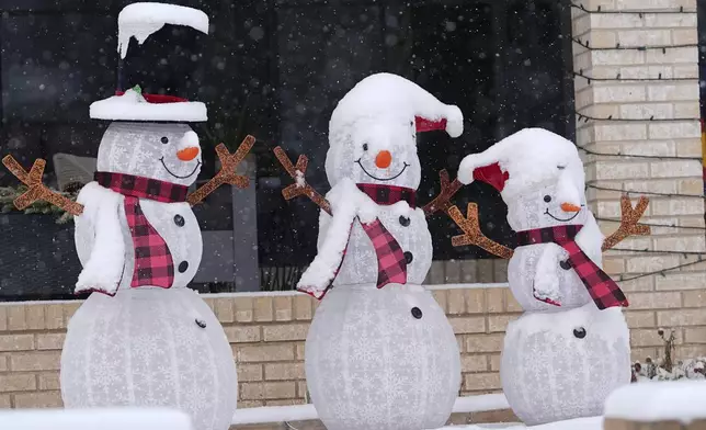 A layer of fresh snow tops holiday lawn characters outside a home as a winter storm sweeps over the intermountain West and across the country Tuesday, Jan. 7, 2025, in Denver. (AP Photo/David Zalubowski)