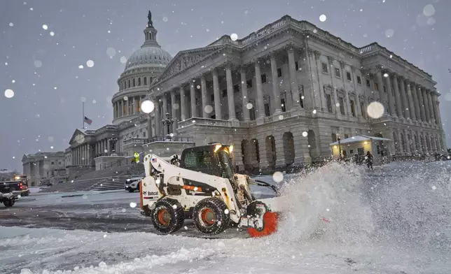 Workers clear the plaza at the Capitol as snow falls ahead of a joint session of Congress to certify the votes from the Electoral College in the presidential election, in Washington, Monday, Jan. 6, 2025. (AP Photo/J. Scott Applewhite)