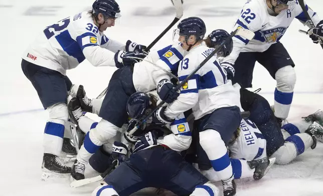 Finland players pile on teammate Benjamin Rautiainen (37) after he scored the winning goal in overtime against Sweden in semifinal game at the world junior hockey championship, Saturday, Jan. 4, 2025 in Ottawa, Ontario. (Adrian Wyld/The Canadian Press via AP)