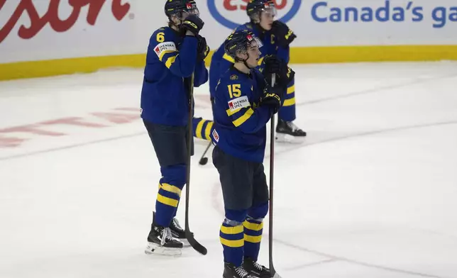 Sweden forward David Edstrom (15) and teammates Axel Hurtig (6) and Axel Sandin Pellikka react after losing in overtime against Finland in semifinal game at the world junior hockey championship, Saturday, Jan. 4, 2025 in Ottawa, Ontario. (Adrian Wyld/The Canadian Press via AP)