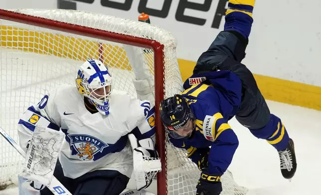 Finland goaltender Petteri Rimpinen looks on as Sweden forward Linus Eriksson flies through the air after clipping the net during the first period of a semifinal game at the world junior hockey championship, Saturday, Jan. 4, 2025 in Ottawa, Ontario. (Adrian Wyld/The Canadian Press via AP)
