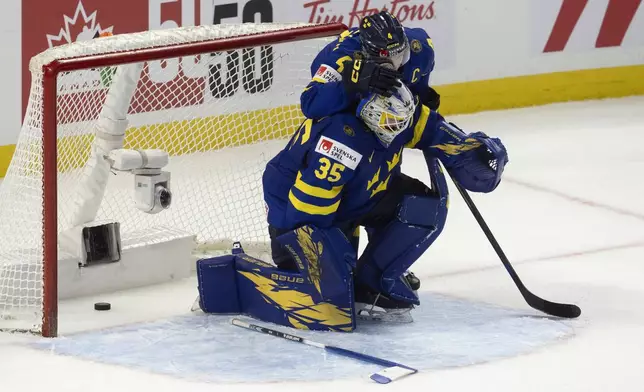 Sweden defenseman Axel Sandin Pellikka(4) hugs goaltender Melker Thelin after losing in overtime against Finland in a semifinal game at the world junior hockey championship, Saturday, Jan. 4, 2025 in Ottawa, Ontario. (Adrian Wyld/The Canadian Press via AP)