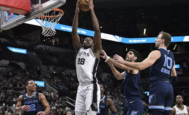 San Antonio Spurs' Charles Bassey (28) tangles with Memphis Grizzlies' Luke Kennard (10) and Santi Aldama, second from front right, during the first half of an NBA basketball game, Friday, Jan. 17, 2025, in San Antonio. (AP Photo/Darren Abate)