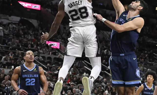 San Antonio Spurs' Charles Bassey (28) dunks against Memphis Grizzlies' Santi Aldama, front right, as Grizzlies guard Desmond Bane (22) watches during the first half of an NBA basketball game, Friday, Jan. 17, 2025, in San Antonio. (AP Photo/Darren Abate)