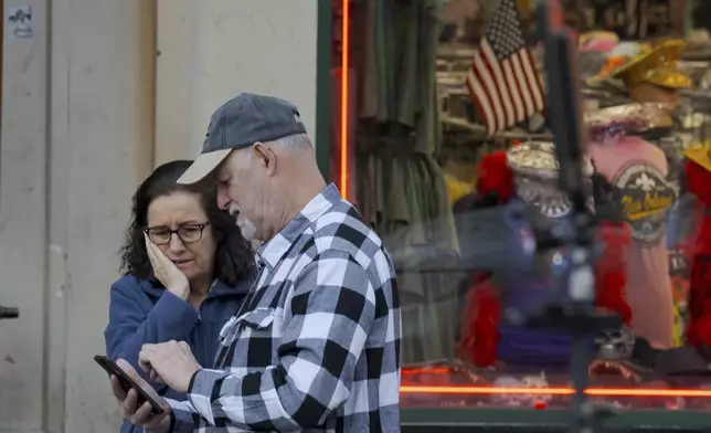 People react at the intersection of Bourbon Street and Canal Street during the investigation after a pickup truck rammed into a crowd of revelers early on New Year's Day, Wednesday, Jan. 1, 2025, in New Orleans. (AP Photo/Matthew Hinton)