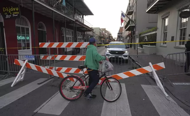 A cyclist passes a police barricade near the scene after a vehicle drove into a crowd on New Orleans' Canal and Bourbon Street, Wednesday Jan. 1, 2025. (AP Photo/Gerald Herbert)