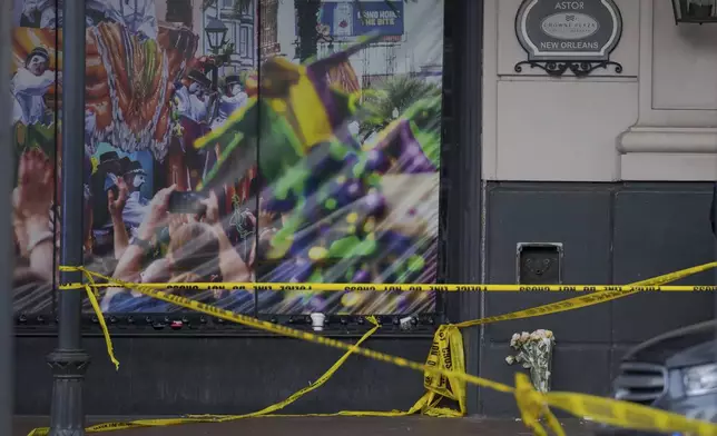 A man left a bouquet of flowers at the intersection of Bourbon Street and Canal Street during the investigation after a pickup truck rammed into a crowd of revelers early on New Year's Day, Wednesday, Jan. 1, 2025, in New Orleans. (AP Photo/Matthew Hinton)