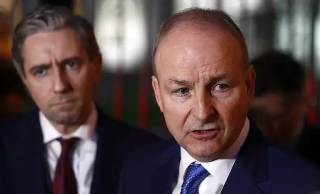 Fianna Fail leader Micheal Martin, right, and Fine Gael's Simon Harris talk to the media outside the government building in Dublin, Wednesday, Jan. 22, 2025.(AP Photo/Peter Morrison)