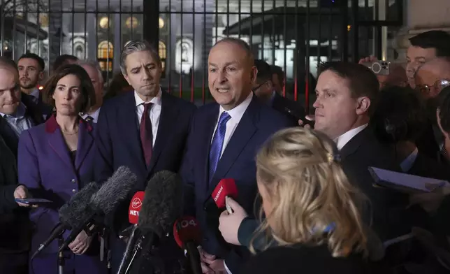Fianna Fail leader Micheal Martin, right and Fine Gael's Simon Harris talk to the media outside the government building in Dublin, Wednesday, Jan. 22, 2025.(AP Photo/Peter Morrison)