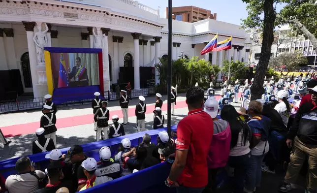 Government supporters and military guard listen to Venezuelan President Nicolas Maduro speak after his swearing-in ceremony for a third term as they watch a live video of him on a screen outside the National Assembly in Caracas, Venezuela, Friday, Jan. 10, 2025. (AP Photo/Matias Delacroix)