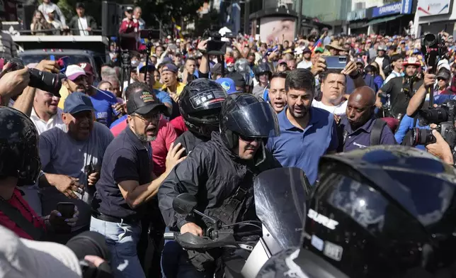 Opposition leader Maria Corina Machado, wearing a helmet, sits on the back of a motorcycle as she is driven away after addressing people at a protest against President Nicolas Maduro in Caracas, Venezuela, Thursday, Jan. 9, 2025, the day before his inauguration for a third term. (AP Photo/Matias Delacroix)