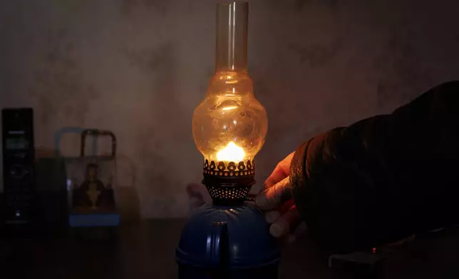 Retired teacher Vasile Donici lights a gas lamp in his home in Copanca, Moldova, Wednesday, Jan. 8, 2025. (AP Photo)