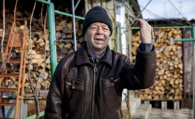 Retired teacher Vasile Donici speaks during an interview with the Associated Press, backdropped by firewood stock in Copanca, Moldova, Wednesday, Jan. 8, 2025. (AP Photo)