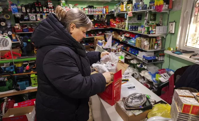 Carina Cazac, a shop owner, checks merchandise in Copanca, Moldova, Wednesday, Jan. 8, 2025. (AP Photo)