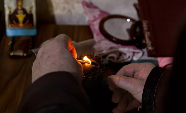 Retired teacher Vasile Donici lights a gas lamp in his home in Copanca, Moldova, Wednesday, Jan. 8, 2025. (AP Photo)