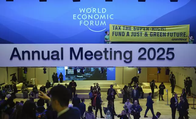 Greenpeace activists show a poster during a protest at the Annual Meeting of World Economic Forum in Davos, Switzerland, Tuesday, Jan. 21, 2025. (AP Photo/Markus Schreiber)