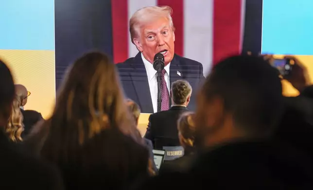 People watch the inauguration of Donald Trump on screens at the Ukraine house alongside the World Economic Forum in Davos, Switzerland, Monday, Jan. 20, 2025. (AP Photo/Markus Schreiber)