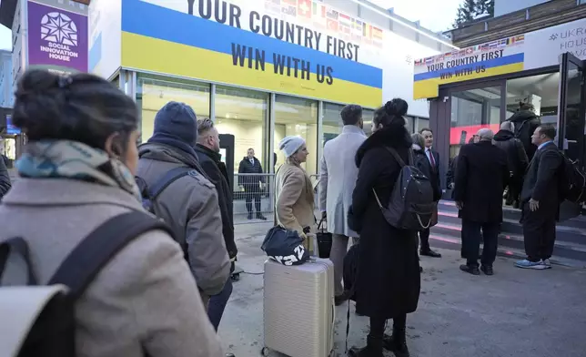 People line up in front of the Ukraine house to watch the inauguration of Donald Trump on screens alongside the World Economic Forum in Davos,Switzerland, Monday, Jan. 20, 2025. (AP Photo/Markus Schreiber)