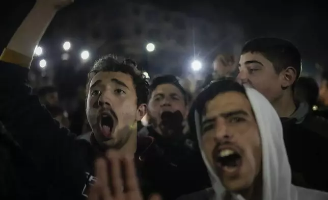 Young men cheer as members of the new security forces, primarily fighters from Hayat Tahrir al-Sham (HTS), fire into the air in celebration after spending most of the day searching for militiamen loyal to ousted President Bashar Assad who refused to surrender their weapons to the new authorities in Homs, Syria, Thursday, Jan. 2, 2025. (AP Photo/Leo Correa)