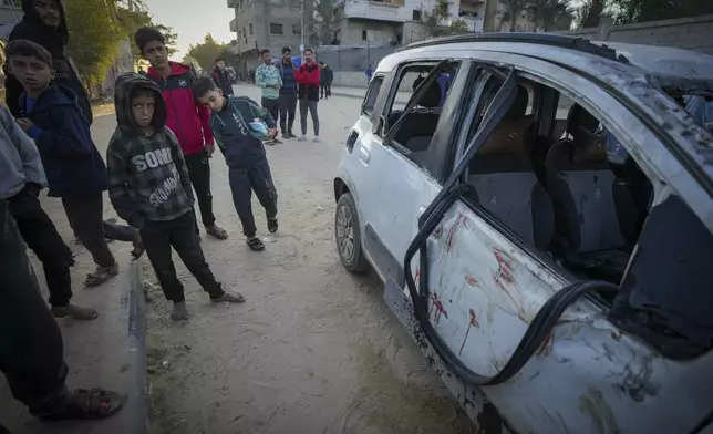 REMOVES NUMBER OF KILLED - Palestinian boys examine a car targeted in an Israeli army strike that killed several of its occupants in Deir al-Balah, central Gaza Strip, Friday, Jan. 3, 2025. (AP Photo/Abdel Kareem Hana)