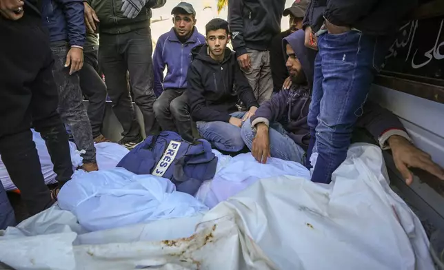 Colleagues and friends mourn over the body of freelance journalist Omar al-Derawi and other victims of overnight Israeli army strikes at multiple locations in central Gaza Strip, at Al-Aqsa Martyrs Hospital in Deir al-Balah, Friday, Jan. 3, 2025. According to Al-Aqsa Martyrs Hospital, 30 people, including 10 women and 7 children, were killed in several attacks overnight in central Gaza. (AP Photo/Abdel Kareem Hana)