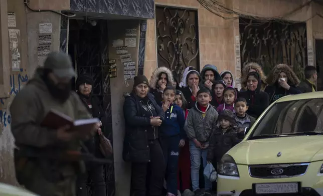 People stand outside their homes as members of the new security forces take part in an operation to detain men suspected of being part of militias or loyalist soldiers of the ousted president Bashar Assad in Homs, Syria, Friday, Jan. 3, 2025. (AP Photo/Leo Correa)