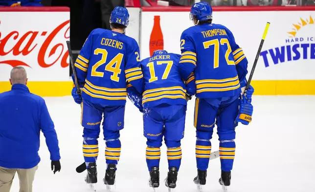 Buffalo Sabres' Jason Zucker (17) is helped off the ice by teammates Dylan Cozens (24) and Tage Thompson (72) after a hit by Ottawa Senators' Brady Tkachuk (not shown) during first-period NHL hockey game action in Ottawa, Ontario, Thursday, Jan. 9, 2025. (Sean Kilpatrick/The Canadian Press via AP)