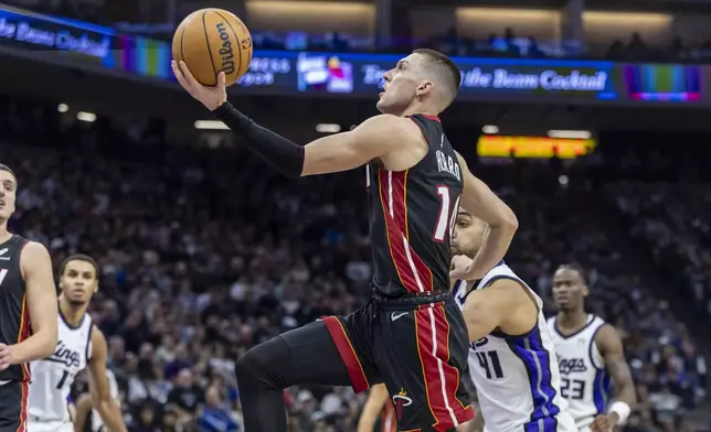 Miami Heat guard Tyler Herro, center, attempts a layup past Sacramento Kings forward Trey Lyles, front right, during the first half of an NBA basketball game Monday, Jan. 6, 2025, in Sacramento, Calif. (AP Photo/Sara Nevis)