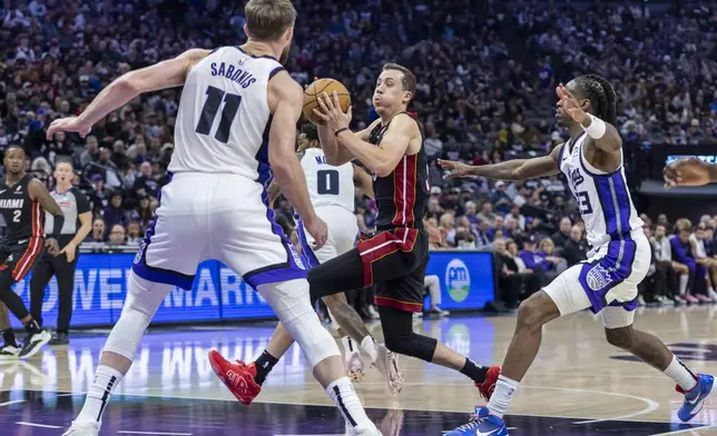 Miami Heat forward Duncan Robinson, center, drives to the basket past Sacramento Kings guard Keon Ellis, right, during the first half of an NBA basketball game Monday, Jan. 6, 2025, in Sacramento, Calif. (AP Photo/Sara Nevis)