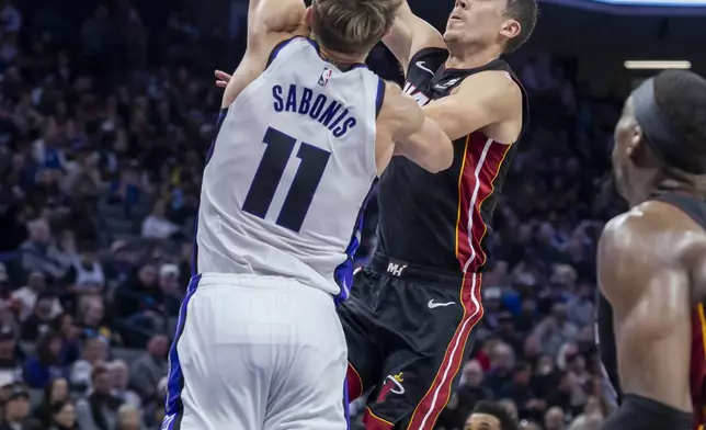 Miami Heat forward Duncan Robinson, center right, attempts a layup over Sacramento Kings center Domantas Sabonis (11) during the first half of an NBA basketball game Monday, Jan. 6, 2025, in Sacramento, Calif. (AP Photo/Sara Nevis)