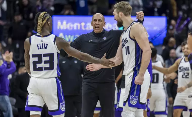 Sacramento Kings interim head coach Doug Christie, center, goes to hug guard Keon Ellis (23) and center Domantas Sabonis, right, during a timeout in double overtime of an NBA basketball game against the Miami Heat, Monday, Jan. 6, 2025, in Sacramento, Calif. The Kings win 123-118 in double overtime. (AP Photo/Sara Nevis)