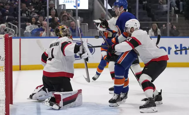 Ottawa Senators goaltender Leevi Merilainen (1) stops a shot by New York Islanders' Noah Dobson (8) as Nick Jensen (3) defends during the second period of an NHL hockey game, Tuesday, Jan. 14, 2025, in Elmont, N.Y. (AP Photo/Frank Franklin II)