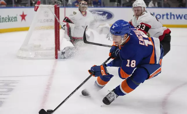 New York Islanders' Pierre Engvall (18) fights for control of the puck with Ottawa Senators' Nikolas Matinpalo (33) as goaltender Leevi Merilainen watches during the second period of an NHL hockey game, Tuesday, Jan. 14, 2025, in Elmont, N.Y. (AP Photo/Frank Franklin II)