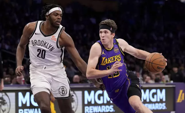 Los Angeles Lakers guard Austin Reaves, right ,drives toward the basket as Brooklyn Nets center Day'Ron Sharpe defends during the first half of an NBA basketball game, Friday, Jan. 17, 2025, in Los Angeles. (AP Photo/Mark J. Terrill)