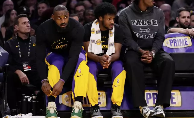 Los Angeles Lakers forward LeBron James, second fro left, and guard Bronny James, second from right sit together during the first half of an NBA basketball game against the Brooklyn Nets, Friday, Jan. 17, 2025, in Los Angeles. (AP Photo/Mark J. Terrill)