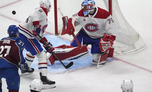 Colorado Avalanche left wing Jonathan Drouin, left, has his shot deflected by Montreal Canadiens defenseman Mike Matheson, center, as goaltender Jakub Dobes protects the net in the second period of an NHL hockey game Saturday, Jan. 4, 2025, in Denver. (AP Photo/David Zalubowski)