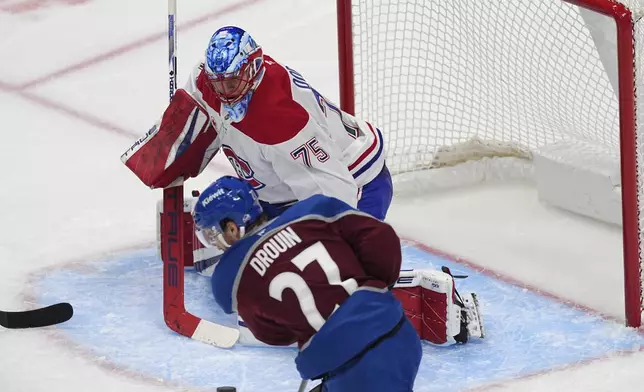 Colorado Avalanche left wing Jonathan Drouin, front, puts a shot on Montreal Canadiens goaltender Jakub Dobes in the second period of an NHL hockey game Saturday, Jan. 4, 2025, in Denver. (AP Photo/David Zalubowski)