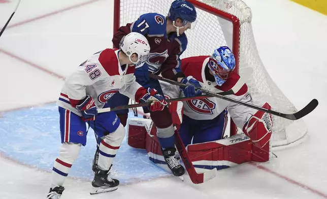 Montreal Canadiens goaltender Jakub Dobes, right, makes a glove save of a shot as defenseman Lane Hutson battles for position with Colorado Avalanche center Parker Kelly in the second period of an NHL hockey game Saturday, Jan. 4, 2025, in Denver. (AP Photo/David Zalubowski)