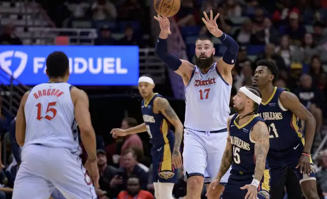 Washington Wizards center Jonas Valanciunas (17) passes to guard Malcolm Brogdon, left, next to New Orleans Pelicans guard Jose Alvarado, front right, during the first half of an NBA basketball game in New Orleans, Friday, Jan. 3, 2025. (AP Photo/Matthew Hinton)