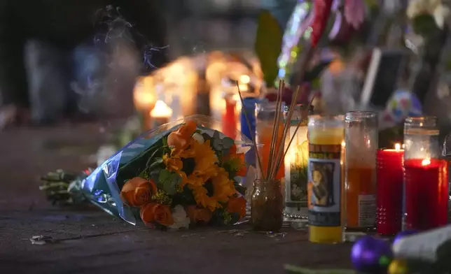 Flowers lie next to candles at a memorial for the victims of a deadly truck attack on New Year's Day in New Orleans, Friday, Jan. 3, 2025. (AP Photo/Gerald Herbert)