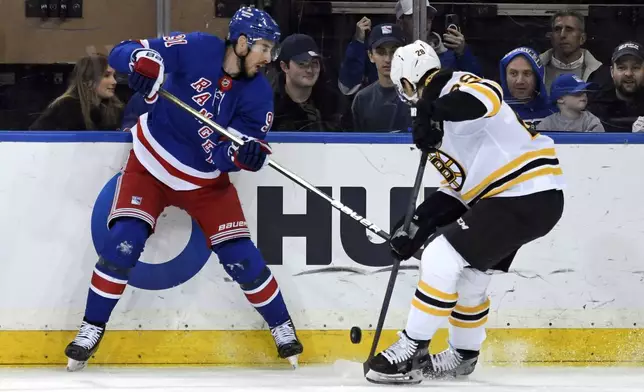 New York Rangers' Reilly Smith, left, and Boston Bruins' Elias Lindholm, right, battle for the puck during the first period of an NHL hockey game Thursday, Jan. 2, 2025, in New York. (AP Photo/Pamela Smith)