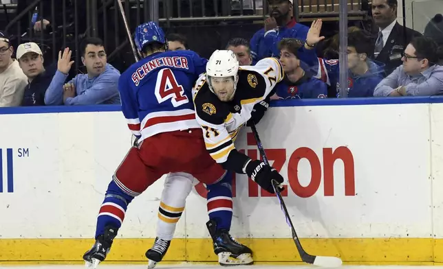 Boston Bruins' Oliver Wahlstrom, right, is pinned against the boards by New York Rangers' Braden Schneider, left, as they battle for the puck during the second period of an NHL hockey game Thursday, Jan. 2, 2025, in New York. (AP Photo/Pamela Smith)